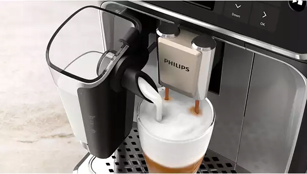 Ekspres Philips 5500 LatteGo przygotowuje kawę. Spienione mleko z pojemnika LatteGo wlewa się do wysokiej szklanki.