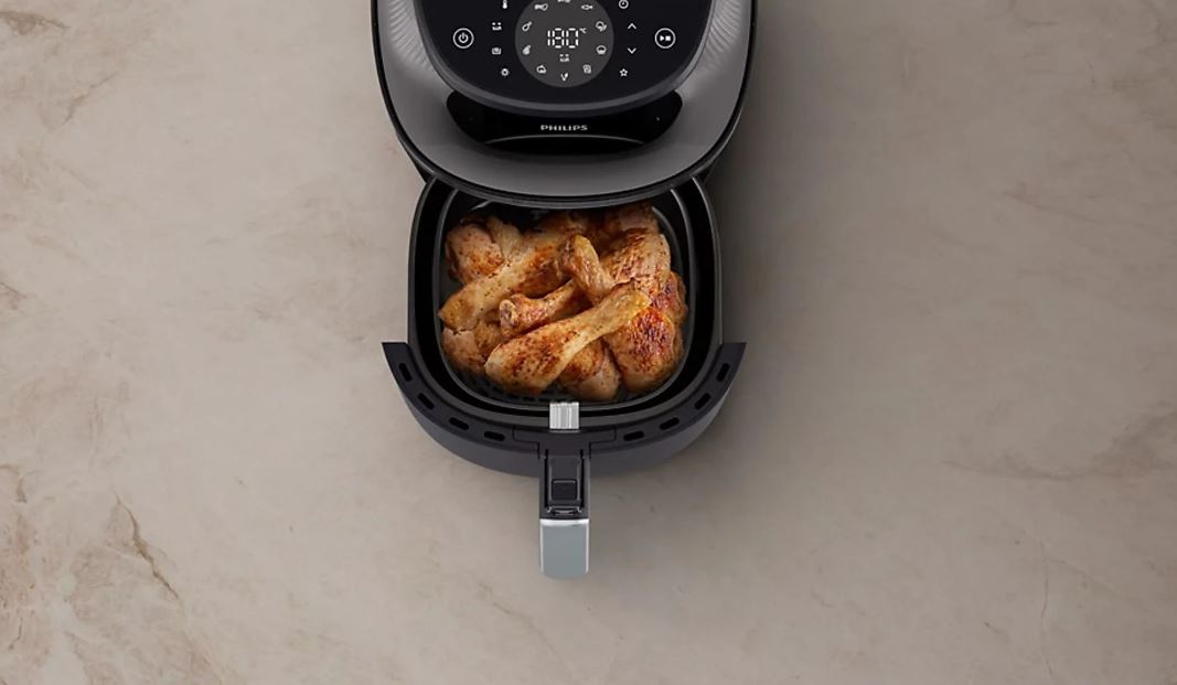 Черная фритюрница Philips Ovi NA322 с открытым ящиком, в котором находится жареная курица.